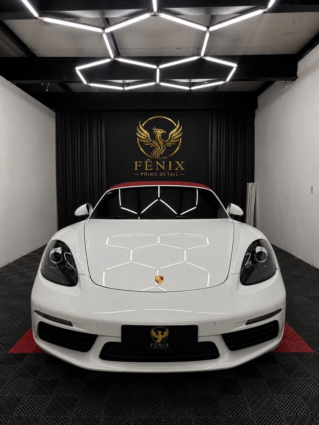 Porsche 718 branco no estúdio da Fênix Prime Detail, com logo dourada ao fundo